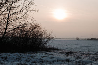 Scenic view of frozen field against sky during sunset