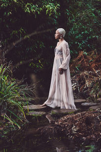 Full length of young woman standing in forest