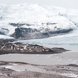 Scenic view of glaciers by snowcapped mountains