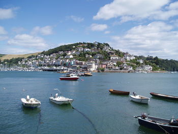 Boats moored on sea by city against sky