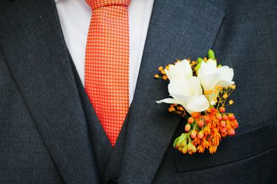 Midsection of groom with flowers in pocket