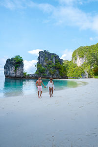 People walking at beach against sky