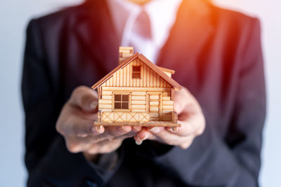 Midsection of man holding model house