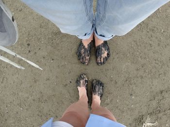 Low section of woman standing on sand at beach