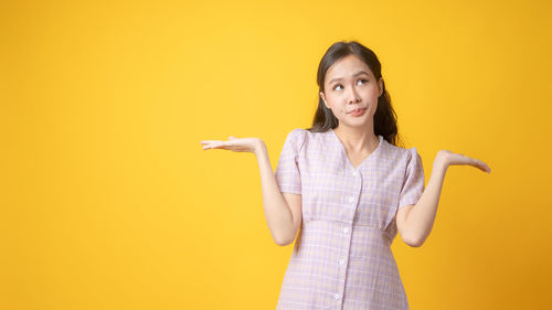 Portrait of a young woman against yellow background