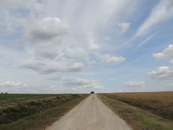 Road amidst field against sky