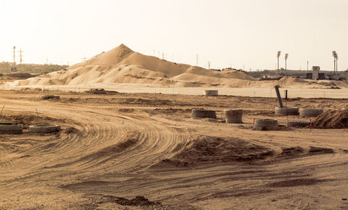 Scenic view of desert against clear sky and a construction site with a pile of sand and tracks