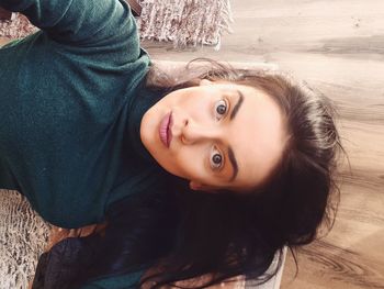 High angle view portrait of young woman on hardwood floor at home