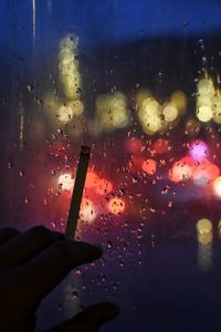 Close-up of hand holding water against sky at night