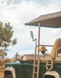 A young adult sitting in a safari car wearing a hat