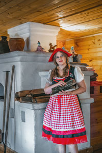 Portrait of young woman standing against wall