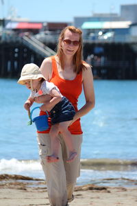 Smiling mother with daughter walking on beach
