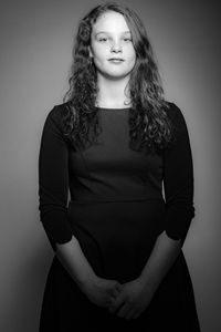 Portrait of young woman standing against white background