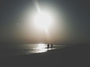 Silhouette man on beach against clear sky during sunset