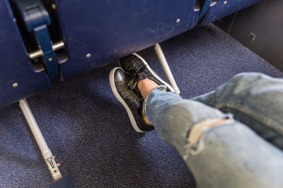 Low section of woman wearing black shoes sitting in airplane