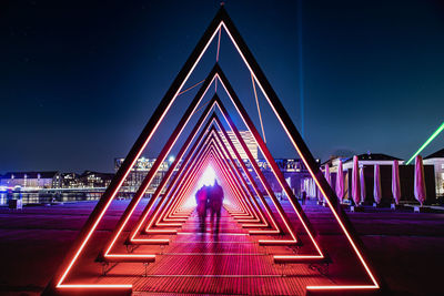 People on illuminated bridge at night