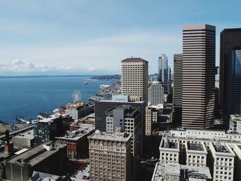 Buildings by sea against sky