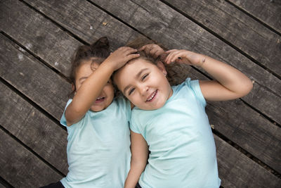 High angle portrait of cute sisters lying on deck