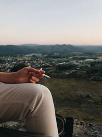 Midsection of man sitting at park against sky