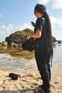 Woman standing on shore against sky