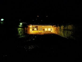 Empty road along illuminated houses at night