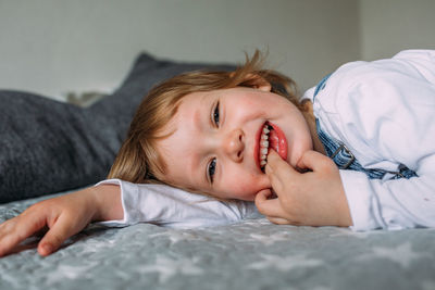 Little cute child is lying and having fun at home on sofa, smiling and laughing