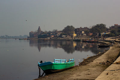 Boats moored in lake against buildings in city