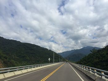 Country road against cloudy sky