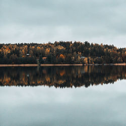 Scenic view of lake by trees against sky