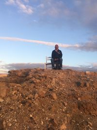 Portrait of man sitting on chair at mountain against sky