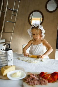 Little girl cooking pizza in the kitchen