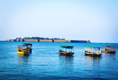 Boats sailing in sea against clear sky