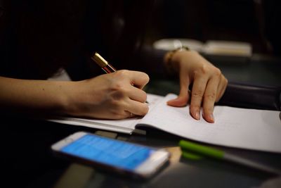 Close-up of hand holding pen while writing on note pad