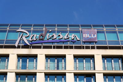 Low angle view of text on building against blue sky