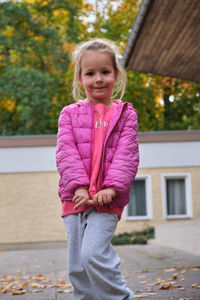 Portrait of young woman standing against building