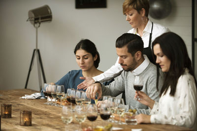 Business people tasting various wine while sitting at table