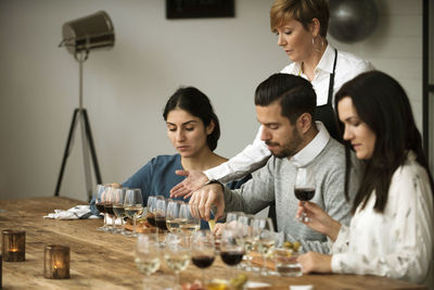 Business people tasting various wine while sitting at table
