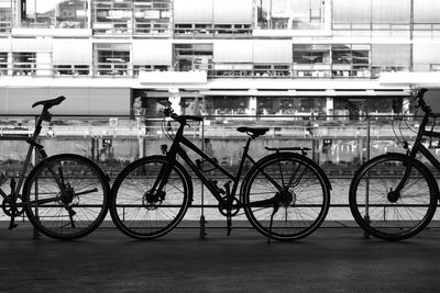 Bicycle parked by railing against buildings in city