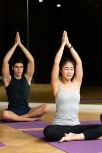 Happy young woman with arms raised on floor