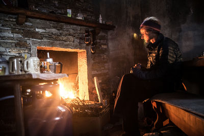 Thoughtful woman sitting by fireplace