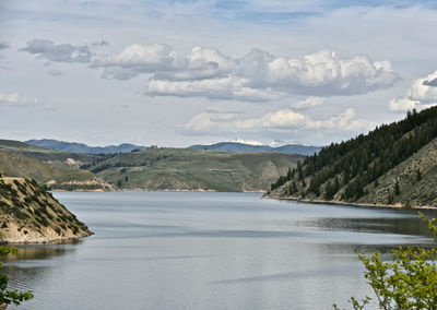 Scenic view of river by mountains against sky