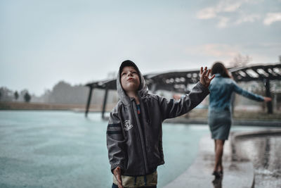 Boy and woman standing in water against sky