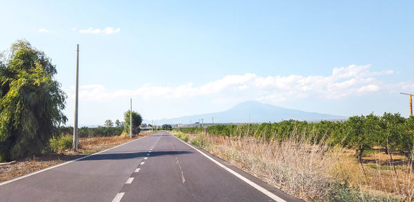 Road leading towards mountains against sky