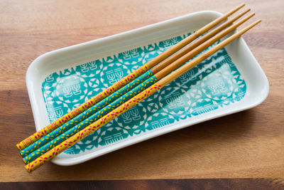 High angle view of chopsticks on plate at wooden table