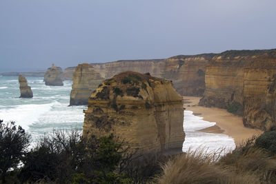 Scenic view of cliff by sea against clear sky