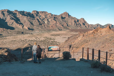 Rear view of people on mountain road against sky