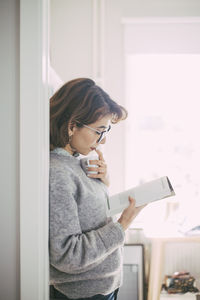 Woman reading book in home office