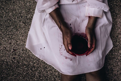 High angle view of zombie holding blood in bowl while sitting on floor