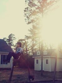 Side view of boy on house against sky