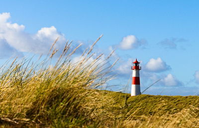 Lighthouse on field against sky